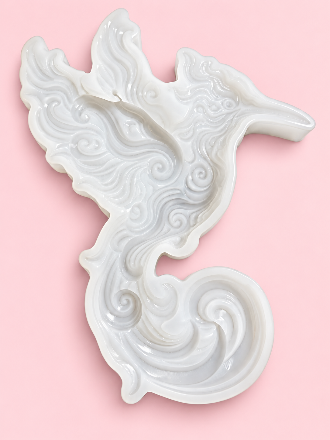 Ornate hummingbird silicone mold with swirling feather design on a pink background